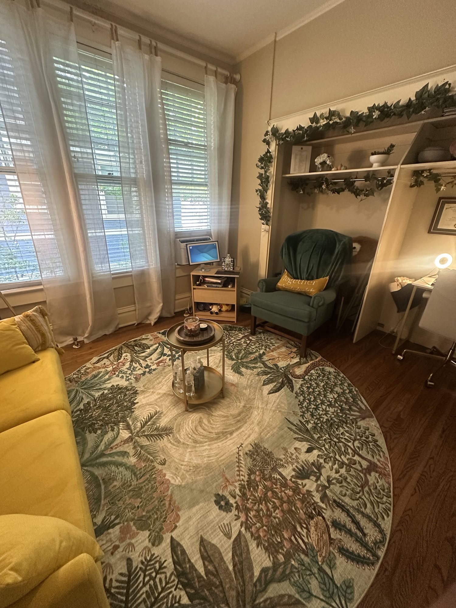 Warm, sunlit therapy office with a yellow sofa, green armchair and patterned rug