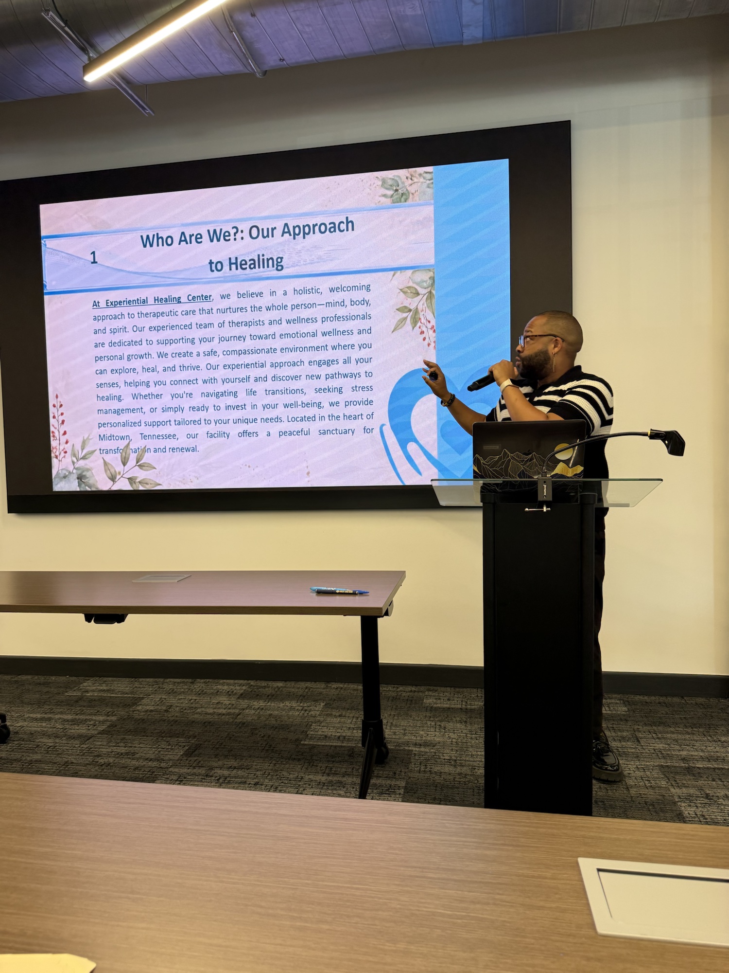 Logan Golden speaking at a podium beside a presentation slide during a talk