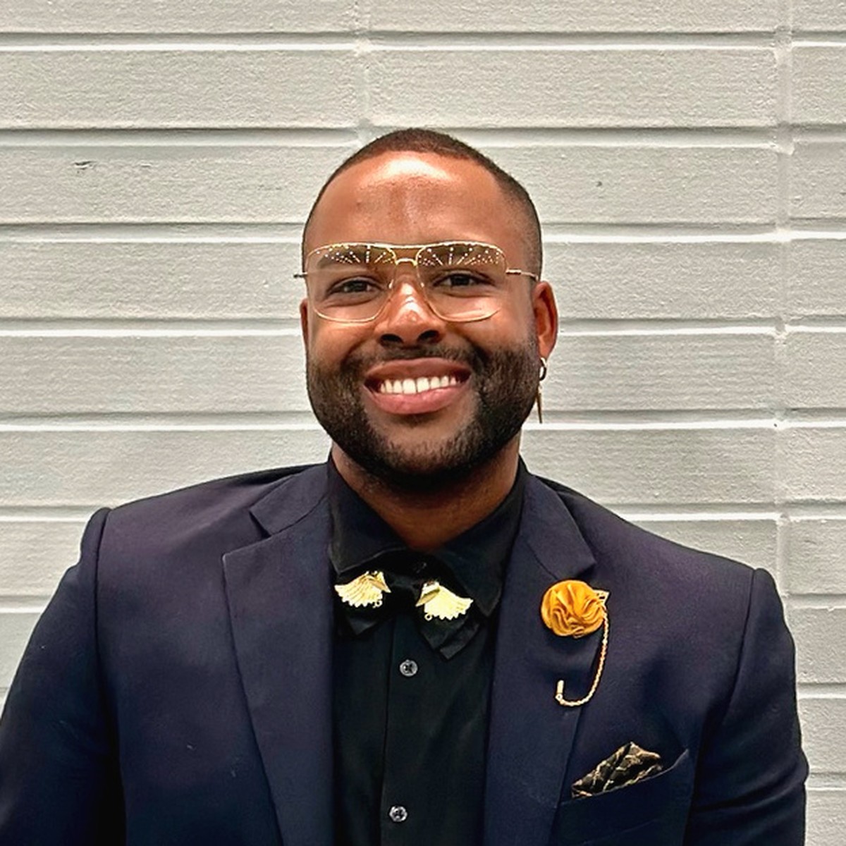 Logan Golden, Licensed Professional Counselor, smiling in a navy blazer against a light brick wall